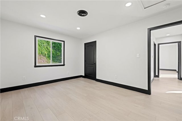 spare room featuring light wood-style flooring, recessed lighting, and baseboards