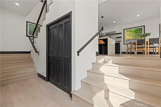 stairway with recessed lighting, wood finished floors, and baseboards