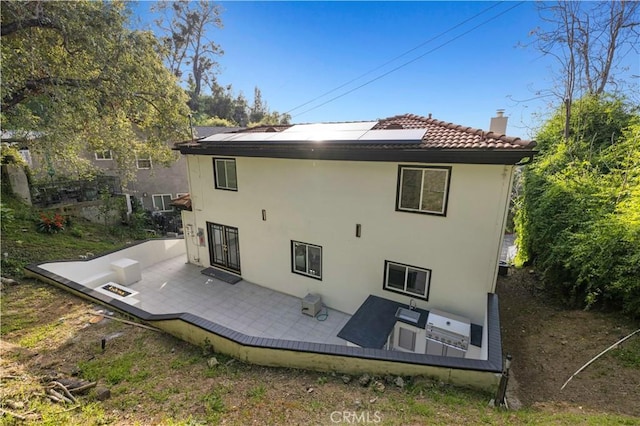 back of property with a chimney, a wooden deck, stucco siding, and a tile roof