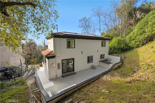 back of house featuring stucco siding, a tile roof, and fence