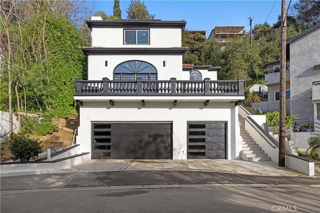 view of front of home with stucco siding, an attached garage, concrete driveway, and stairs