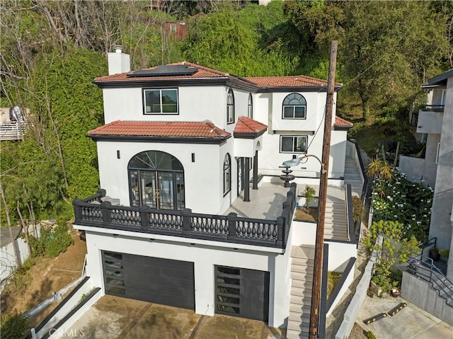 view of front facade featuring stairway, stucco siding, a chimney, and a garage