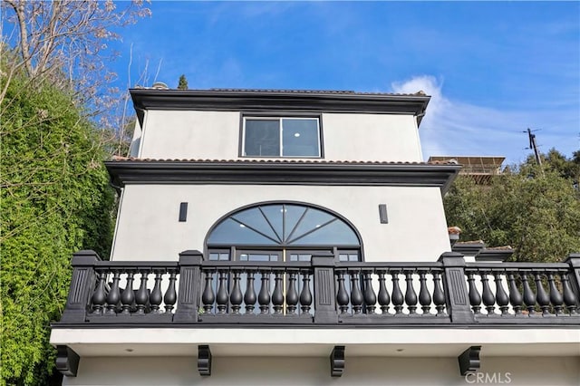 rear view of property with stucco siding and a balcony