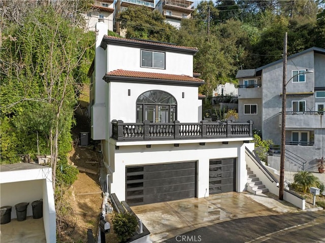 mediterranean / spanish home featuring driveway, stucco siding, stairs, a garage, and a tile roof