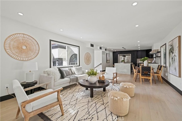 living area with recessed lighting, visible vents, baseboards, and light wood finished floors