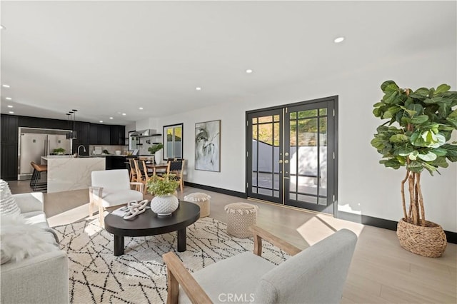 living room with recessed lighting, french doors, baseboards, and light wood finished floors