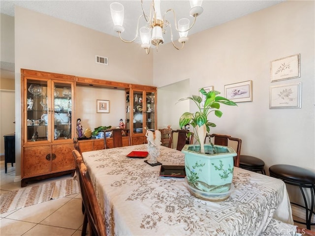 dining room with light tile patterned floors, visible vents, an inviting chandelier, and a towering ceiling