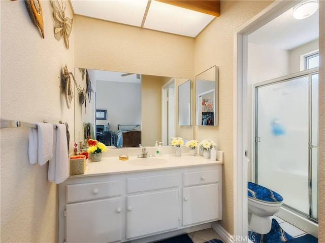 ensuite bathroom with tile patterned floors, toilet, connected bathroom, a shower stall, and vanity