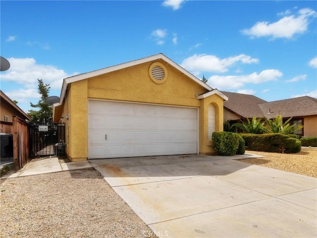 ranch-style house featuring fence, stucco siding, a garage, driveway, and a gate