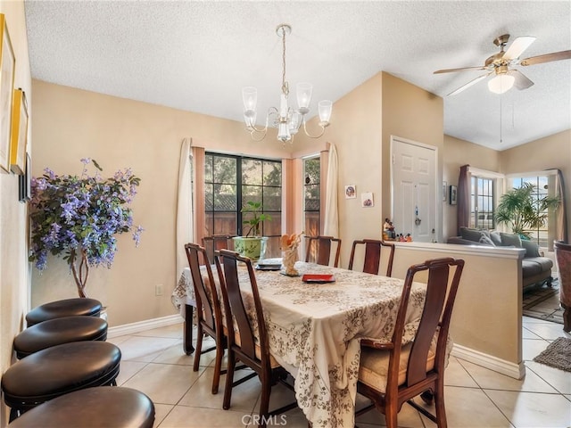 dining room with light tile patterned flooring, ceiling fan with notable chandelier, baseboards, and a textured ceiling