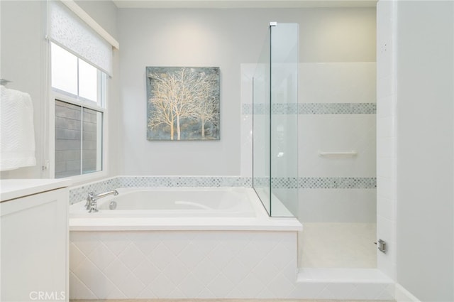 bathroom featuring a garden tub, walk in shower, and vanity