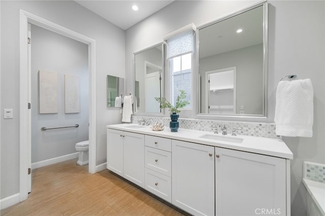 full bath featuring double vanity, toilet, baseboards, and a sink