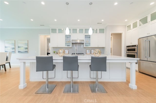 kitchen with a breakfast bar, tasteful backsplash, under cabinet range hood, and stainless steel appliances