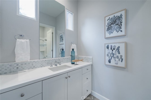 bathroom featuring baseboards, backsplash, walk in shower, and vanity