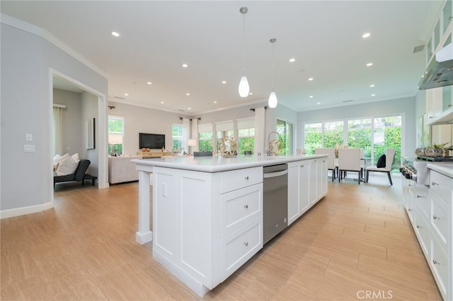 kitchen with open floor plan, light countertops, appliances with stainless steel finishes, white cabinets, and a kitchen island with sink