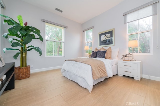 bedroom featuring visible vents, baseboards, and light wood finished floors