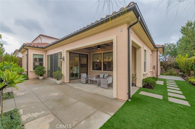 back of property featuring a yard, stucco siding, outdoor lounge area, a tiled roof, and a patio area