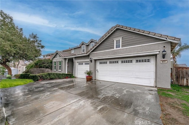 view of front of property featuring fence, an attached garage, stucco siding, concrete driveway, and a tiled roof