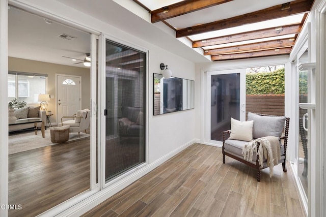 sunroom / solarium featuring beam ceiling, visible vents, and a ceiling fan