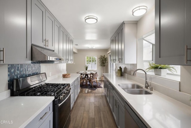 kitchen featuring gray cabinets, a sink, light countertops, appliances with stainless steel finishes, and under cabinet range hood