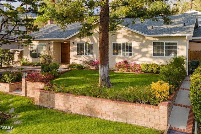 ranch-style house with stucco siding, a front yard, and a shingled roof