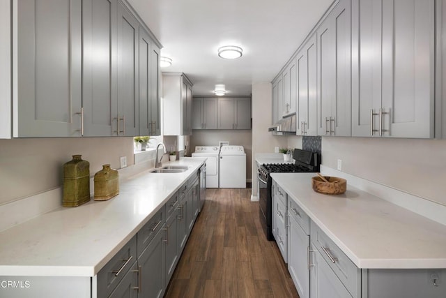 kitchen with a sink, gray cabinetry, black range with gas cooktop, under cabinet range hood, and washing machine and dryer