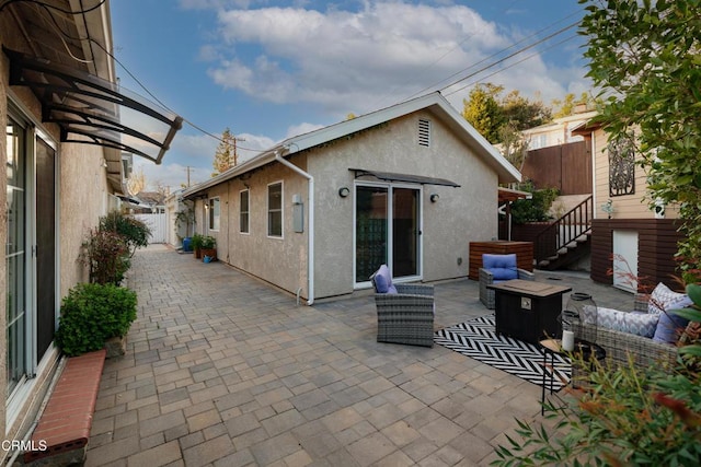 rear view of property featuring a patio, an outdoor hangout area, fence, and stucco siding