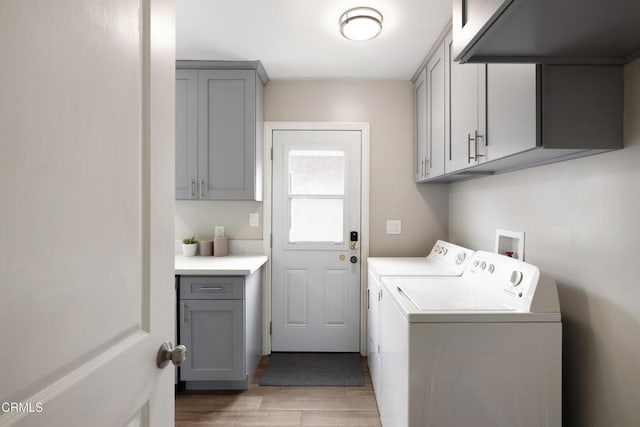 clothes washing area with cabinet space, independent washer and dryer, and light wood-type flooring