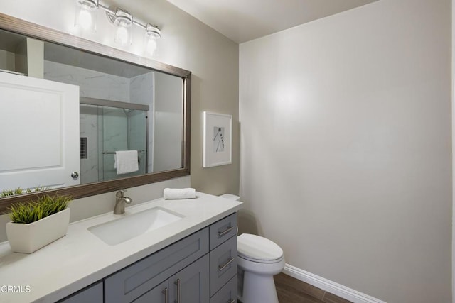 full bathroom with vanity, wood finished floors, baseboards, a marble finish shower, and toilet