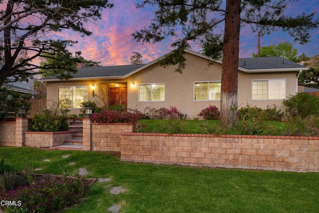 ranch-style home with a yard and stucco siding