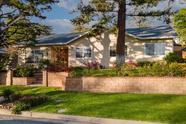 ranch-style house with a front lawn and stucco siding