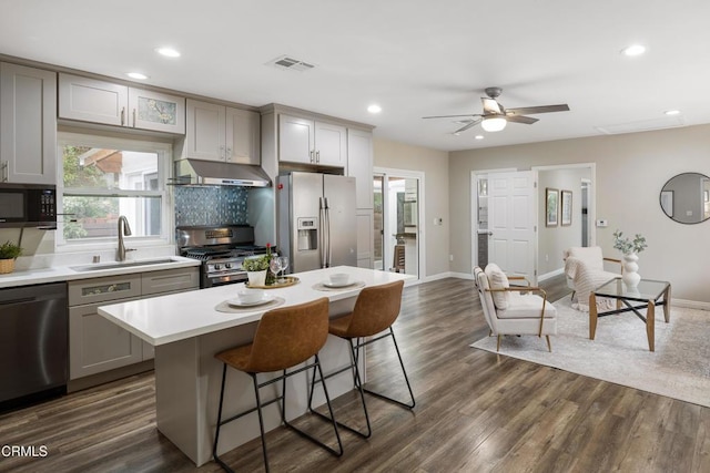 kitchen with visible vents, gray cabinetry, a sink, under cabinet range hood, and appliances with stainless steel finishes