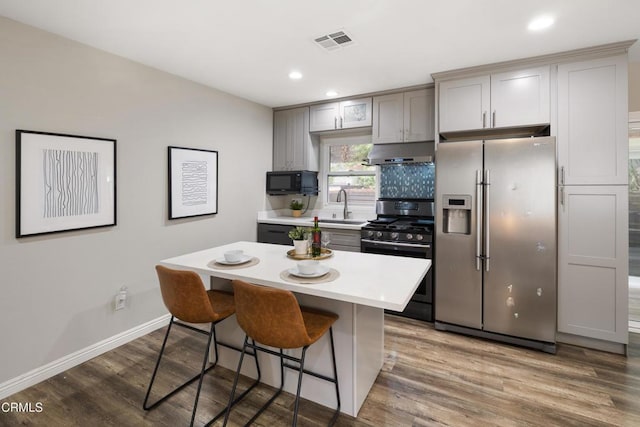 kitchen with visible vents, black appliances, under cabinet range hood, a sink, and light countertops