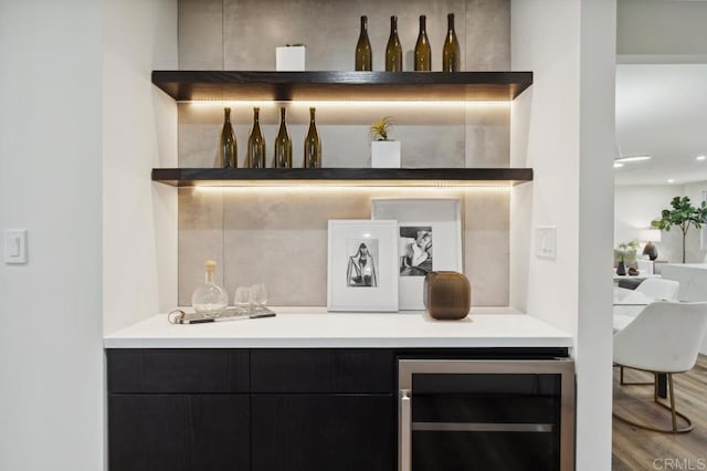 bar featuring beverage cooler, a dry bar, and wood finished floors