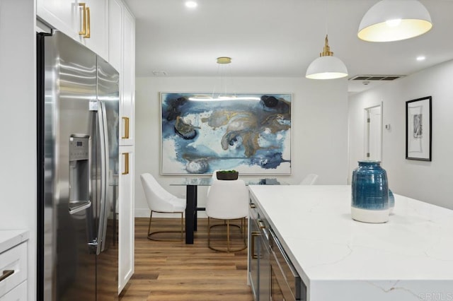 kitchen with light wood-type flooring, light stone counters, a kitchen island, white cabinets, and stainless steel fridge with ice dispenser