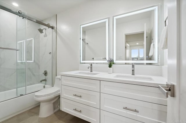 full bath featuring a sink, combined bath / shower with glass door, toilet, and double vanity