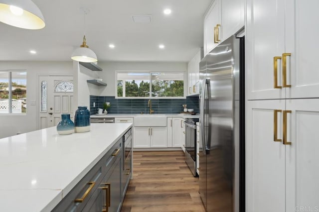 kitchen featuring white cabinetry, light stone countertops, backsplash, and stainless steel appliances