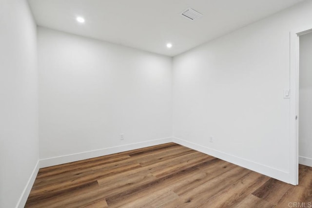 spare room featuring recessed lighting, wood finished floors, visible vents, and baseboards