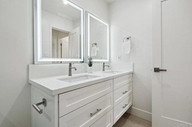 bathroom with a sink, baseboards, double vanity, and tile patterned flooring