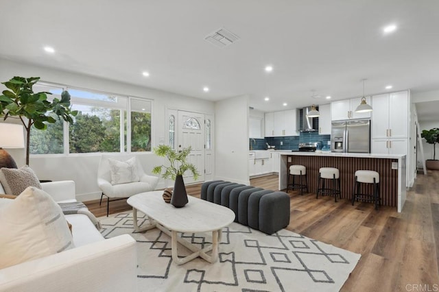 living room with light wood-type flooring, visible vents, and recessed lighting