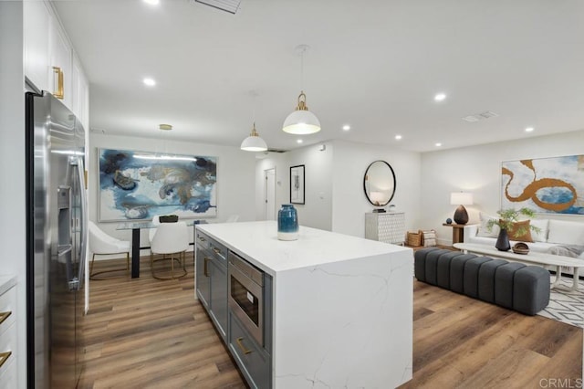 kitchen featuring a kitchen island, open floor plan, recessed lighting, appliances with stainless steel finishes, and wood finished floors