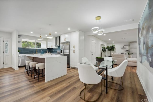 dining room with light wood finished floors, a notable chandelier, recessed lighting, and visible vents