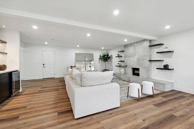 living area with beverage cooler, beamed ceiling, recessed lighting, and light wood-type flooring