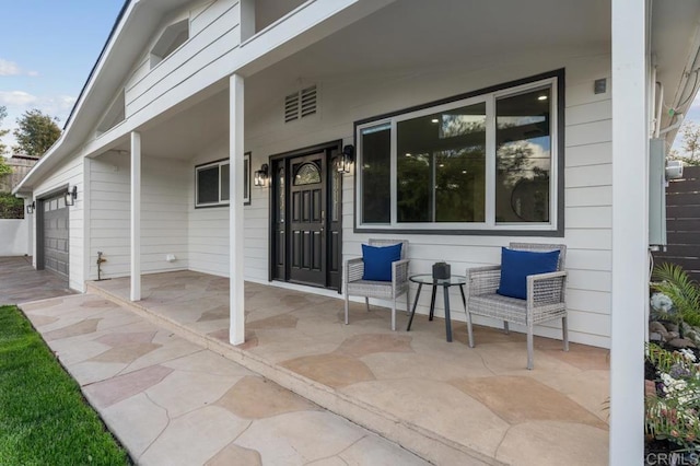 view of patio / terrace featuring a porch and an attached garage