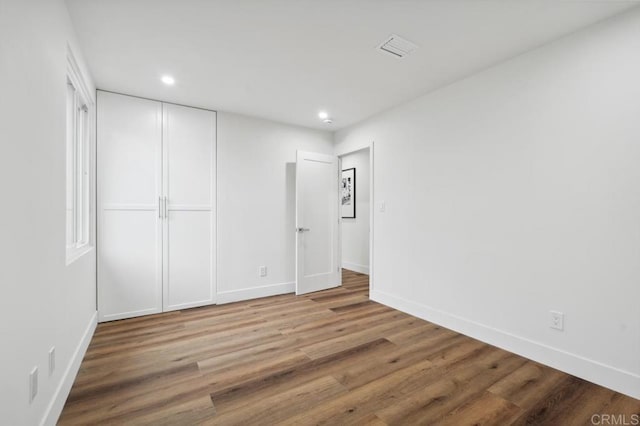 unfurnished bedroom featuring visible vents, wood finished floors, recessed lighting, a closet, and baseboards