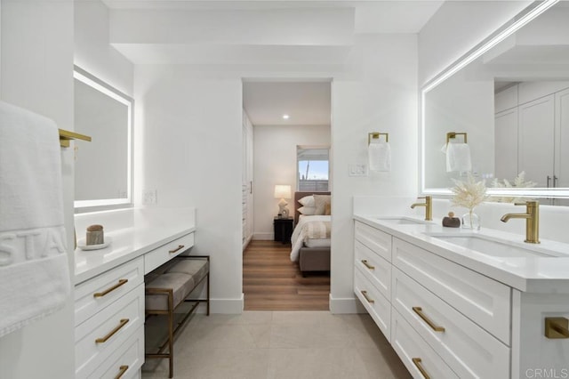 full bath featuring double vanity, ensuite bathroom, baseboards, and a sink