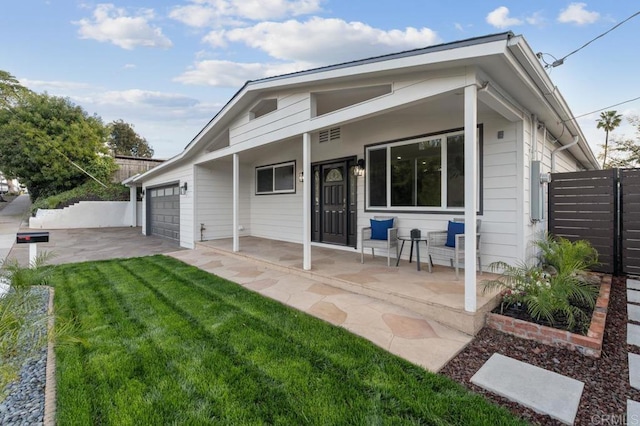 back of property featuring fence, driveway, a porch, an attached garage, and a yard