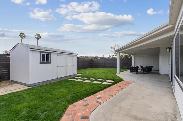 view of yard with a storage unit, an outbuilding, a fenced backyard, and a patio area