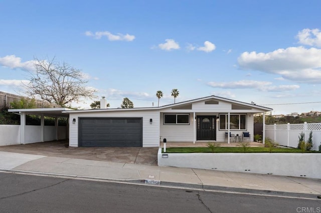 view of front of home featuring a porch, fence, concrete driveway, an attached garage, and a carport