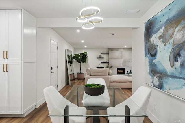 dining room with wood finished floors, visible vents, baseboards, recessed lighting, and a tiled fireplace